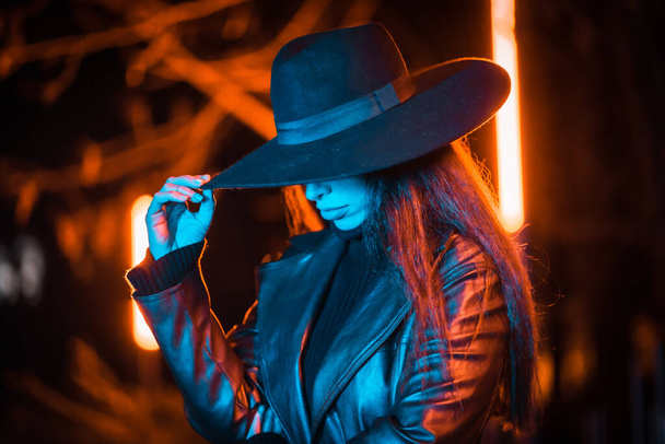 Girl in a hat walking at night in a park, pensive and enjoying the tranquility without people, blue light - Foto, Bild