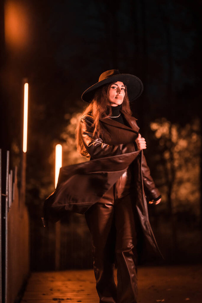 Pretty Caucasian girl with hat walking at night in a park. Winter fashion and lifestyle at night, vertical photo - Valokuva, kuva