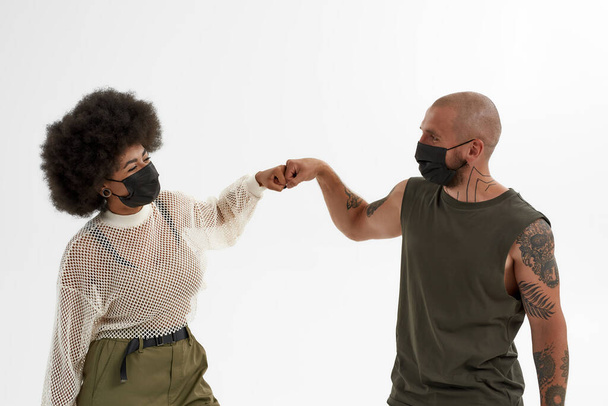 Hombre y chica en máscaras médicas golpeando puños - Foto, imagen