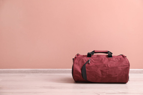 Red sports bag on floor near pink wall, space for text - Zdjęcie, obraz