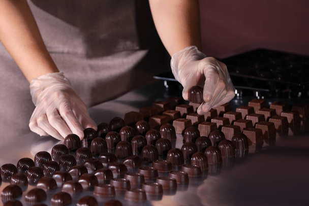 Woman with delicious candies at production line, closeup - Photo, image