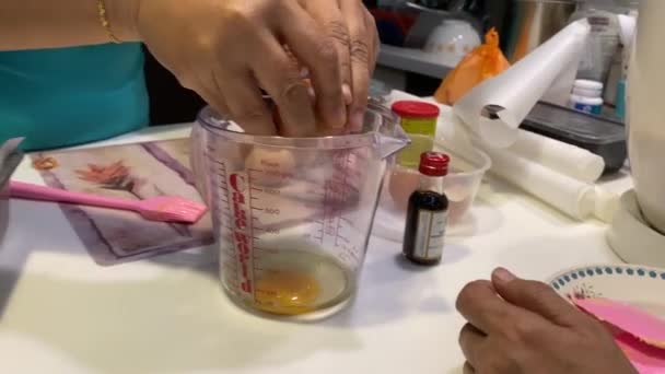 cracking eggshells and dropping eggs into measuring cup for baking butter cake - Footage, Video