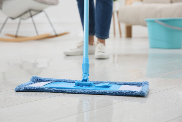 Woman cleaning parquet floor with mop at home, closeup - Fotó, kép