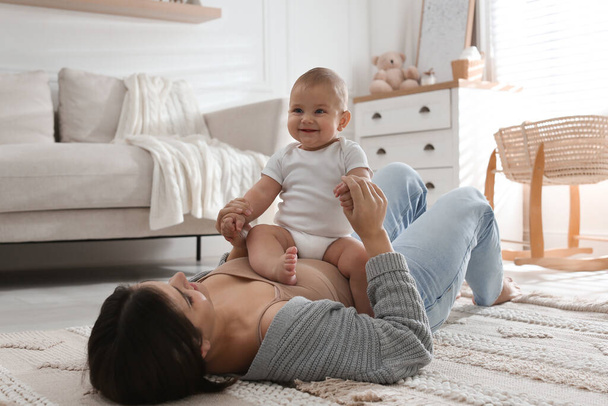 Happy young mother with her cute baby on floor at home - Foto, afbeelding