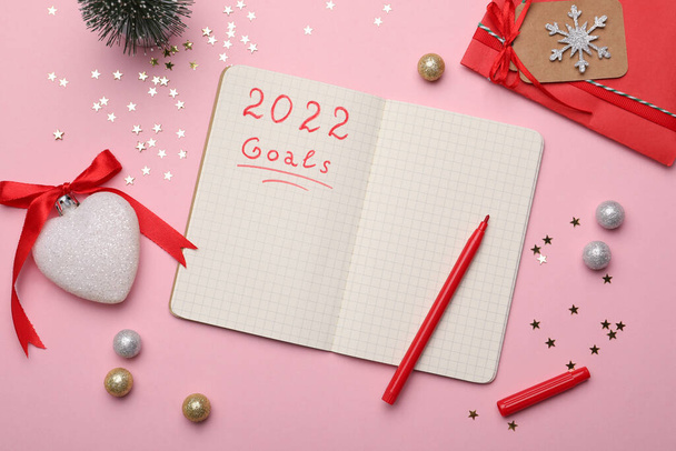2022年新年の計画目標。ピンクの背景のノートとお祝いの装飾、フラットレイ - 写真・画像