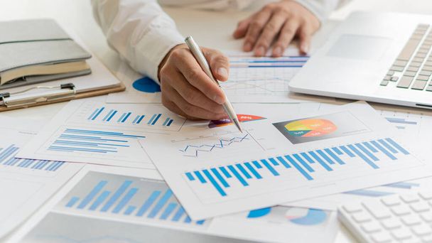business woman holding documents with financial statistics Data analysis charts and graphs and calculators. financial concept close-up holding a pen and pointing at a financial document - Foto, imagen