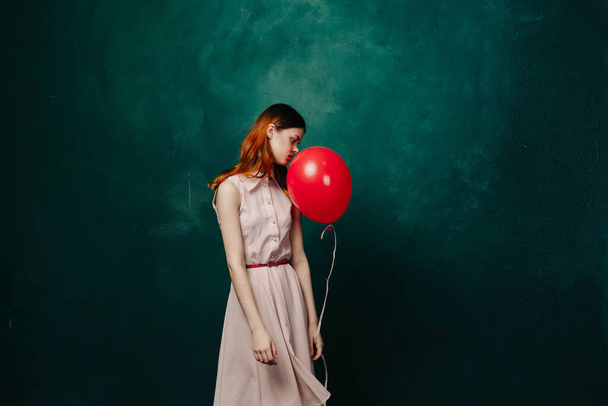 woman with red balloon on green background holiday fun - 写真・画像