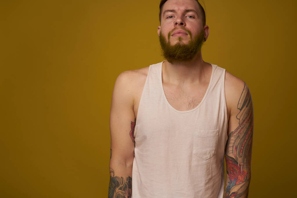 bearded man in white t-shirt with tattoos on his arms posing macho - Foto, Imagem