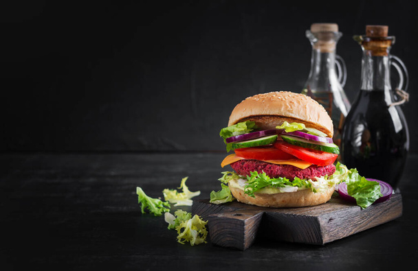 Hamburguesas veganas saludables de remolacha con tomate, pepino, cebolla roja y salsa. Fondo oscuro. Copiar espacio. - Foto, imagen