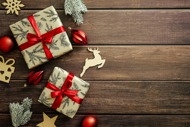 Сельский рождественские подарочные коробки украшены красной лентой лук. деревянные украшения, еловые ветви на деревянном столе. Квартира лежала, вид сверху. Рождественская открытка. - Фото, изображение