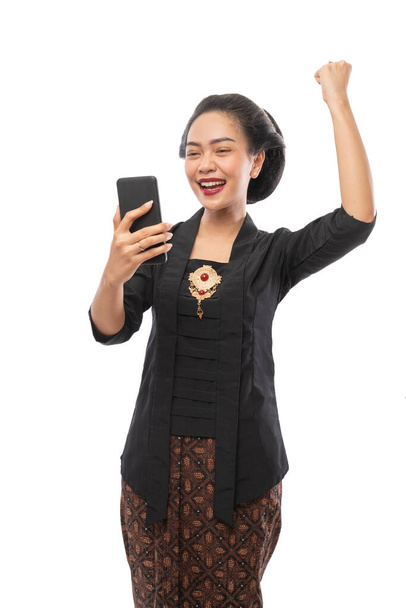 woman with kebaya clothes happy looking at phone - 写真・画像