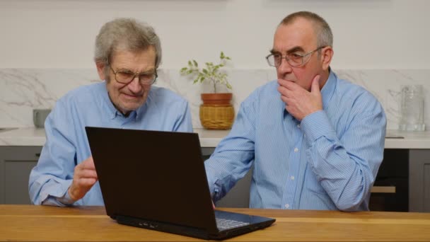 Starší starší starší muži pomocí notebooku při relaxaci doma - Záběry, video