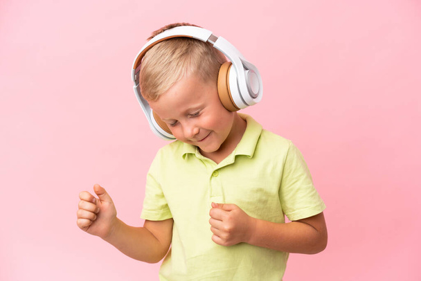 Little Russian boy isolated on pink background listening music - Photo, Image
