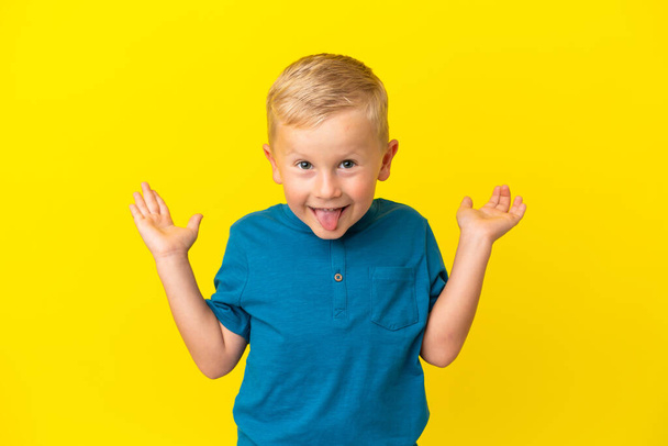 Маленький русский мальчик изолирован на желтом фоне с шокированным выражением лица - Фото, изображение