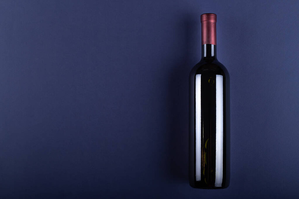 Bottle of red wine without a label on a purple paper background. Mockup drink with place for you label and text. Space for text.Top view. - Foto, Bild