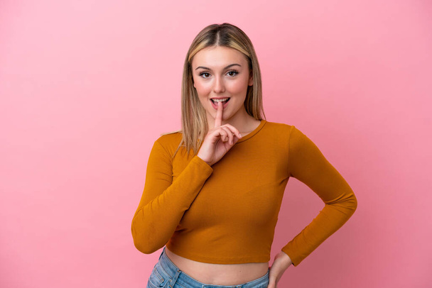 Young caucasian woman isolated on pink background showing a sign of silence gesture putting finger in mouth - Photo, Image