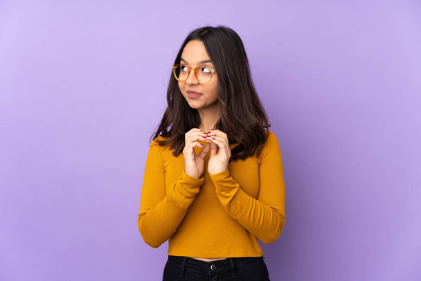 Young mixed race woman isolated on purple background scheming something - Photo, Image