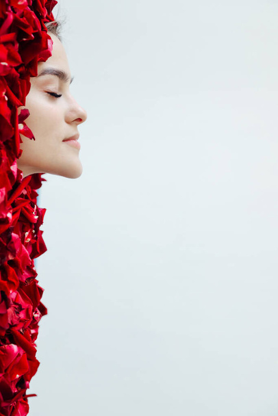 beautiful face of a woman in red rose petals - Foto, Imagen
