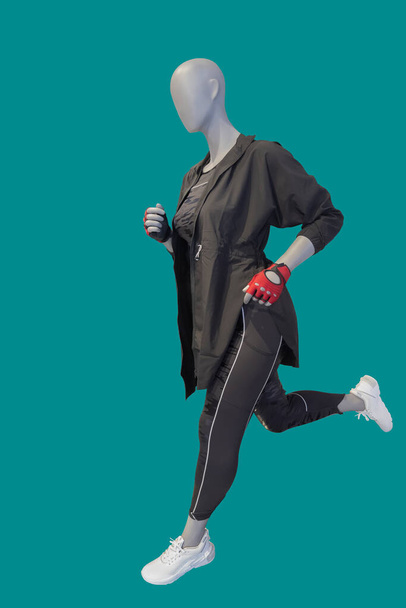 Imagen completa de un maniquí de exhibición femenina corriendo con ropa deportiva aislada sobre un fondo verde - Foto, Imagen