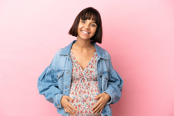 Mladá těhotná žena přes izolované růžové pozadí smích - Fotografie, Obrázek
