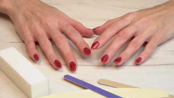 Chica meneando los dedos preparándose para una manicura. Servicio de manicura hecho a sí mismo. Manicurista pinta las uñas con esmalte de gel rosa. Uñas rojas cuidadas. Aplicación de esmalte de uñas. - Metraje, vídeo