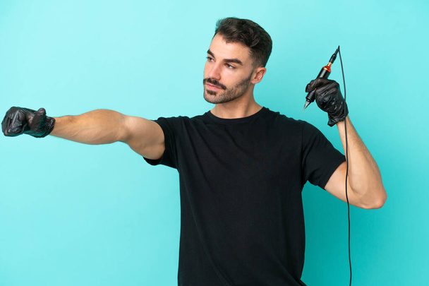 Young tattoo artist man isolated on blue background giving a thumbs up gesture - Foto, Imagem