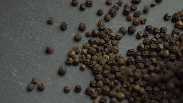 Zwarte peper wordt op de draaitafel gegoten, zwarte peperkorrels - Video
