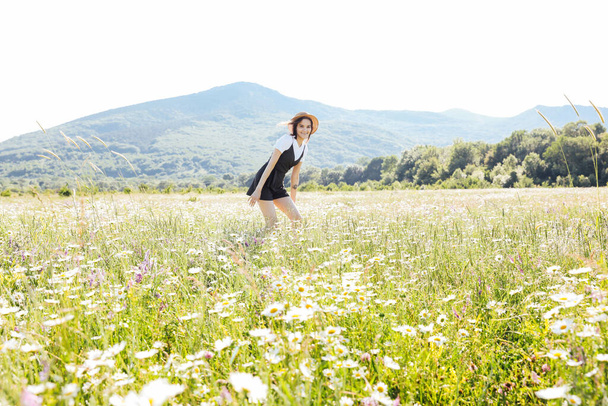 デイジーと畑を走り回るドレスを着た美しい女性 - 写真・画像
