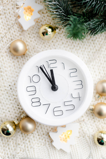 Часы на пляже с гирляндой. Белые часы. Уютные вибрации. Домашний комфорт Новый год и Рождество. Украшение - Фото, изображение