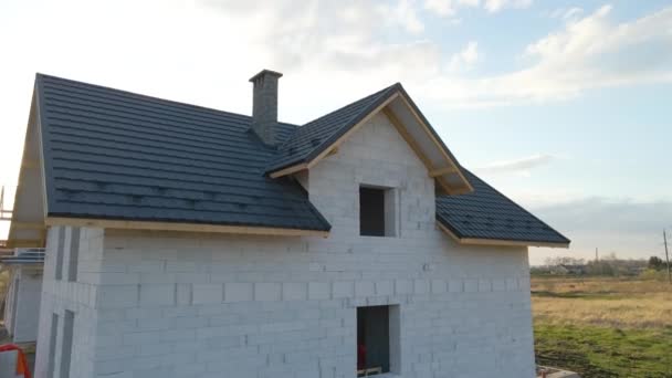 Vista aérea de casa inacabada con paredes de hormigón ligero aireado y marco de techo de madera cubierto con azulejos metálicos en construcción - Metraje, vídeo