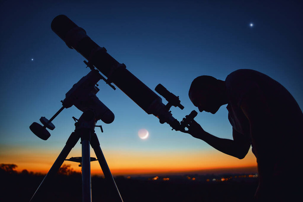 Силуэт человека, телескопа и сельской местности под звездным небом. - Фото, изображение