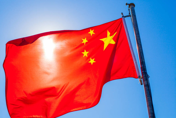 Nationale vlag van de Volksrepubliek China, Vijf-sterren rode vlag, wapperend op de wind, blauwe lucht op de achtergrond. - Foto, afbeelding