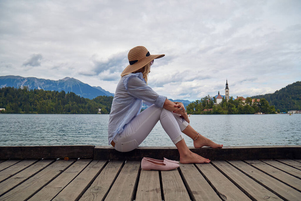 Jonge volwassen toeristische vrouw genieten van barefeet op een meer houten pier. - Foto, afbeelding
