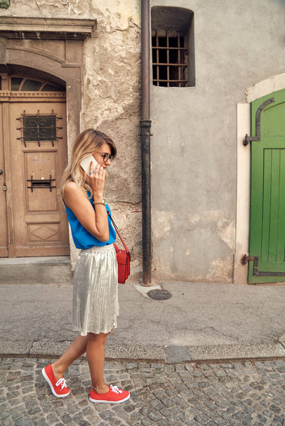Молодая милая женщина с помощью смартфона на улице. - Фото, изображение