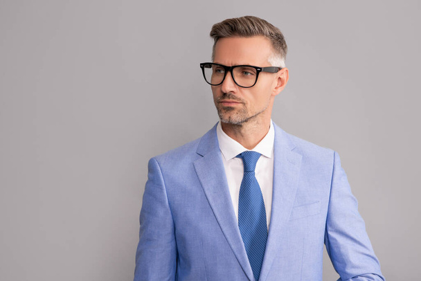 mature businessman in elegant jacket and eyeglasses on gray background, copy space, formalwear - Foto, afbeelding
