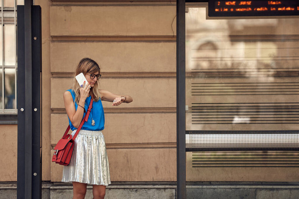 Молода біла жінка чекає громадського транспорту на вокзалі
. - Фото, зображення
