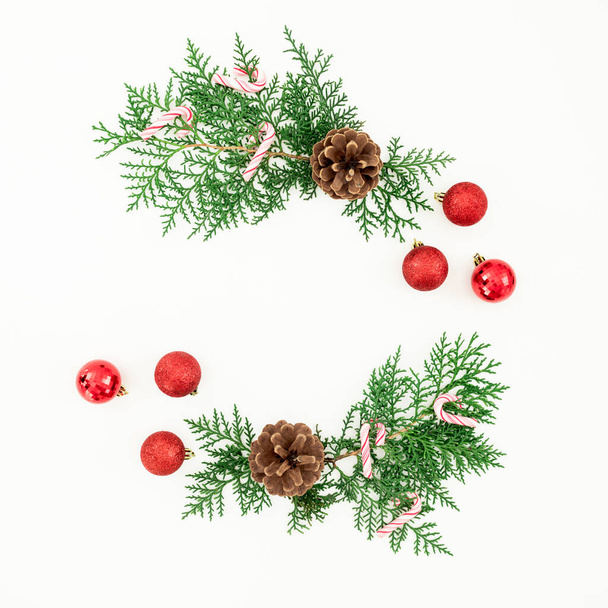Frohe Weihnachten Rahmenkomposition mit grünen Zweigen und roten Kugeln auf weißem Hintergrund. Flache Lage, Draufsicht - Foto, Bild