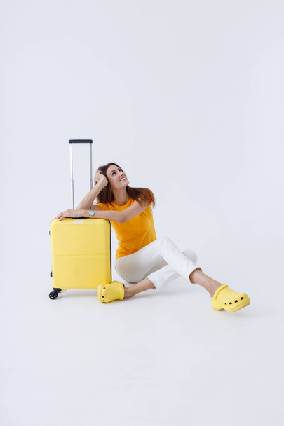Весела жінка мандрівник сидить біля багажної сумки
 - Фото, зображення