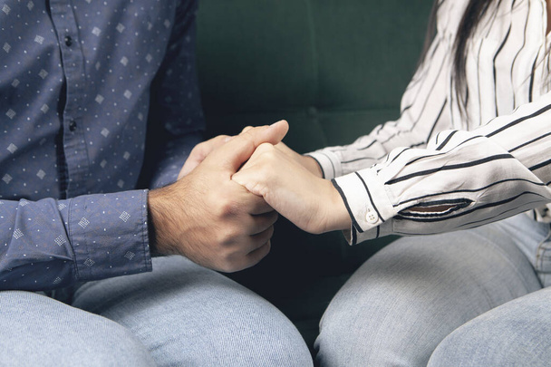 young couple holding hands while sitting on the couch - Photo, Image