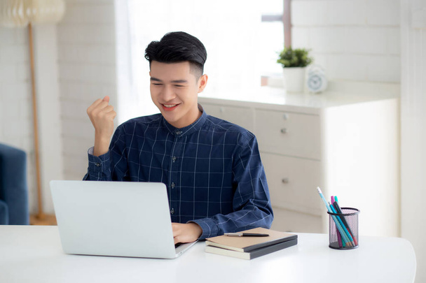 Happy young businessman work on laptop computer finish with excited and success on desk at home, business man using notebook with achievement and surprised, freelance or employee, satisfied and glad. - Photo, Image