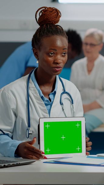 Medical specialist with horizontal green screen on digital tablet - 写真・画像