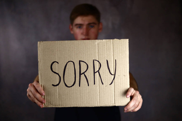 Guy holding a paper with the word Sorry - Photo, Image