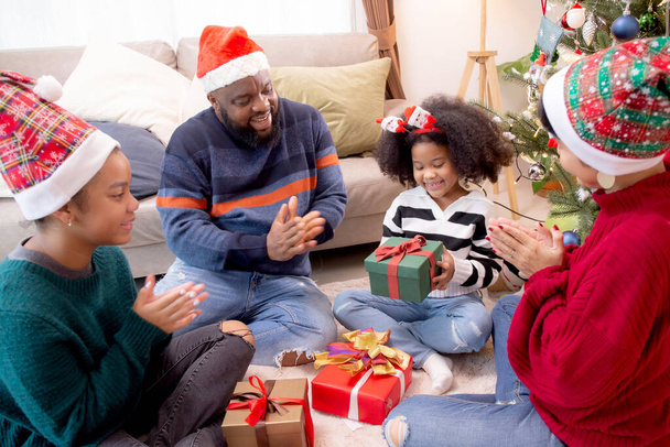 幸せな家族の父と母は家でクリスマスの日に娘と一緒にギフトボックスを与える、家で楽しむ親の驚くべき子供たちとクリスマス、感謝祭の前夜、メリークリスマス. - 写真・画像