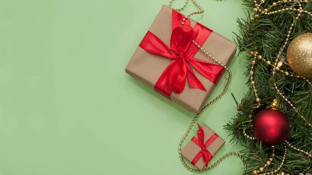 gifts of different sizes with red ribbons on a green background with Christmas decor - Foto, immagini