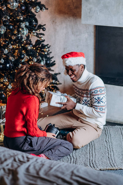 Afroamerykanin mężczyzna przedstawia dziewczyna Boże Narodzenie prezent - Zdjęcie, obraz