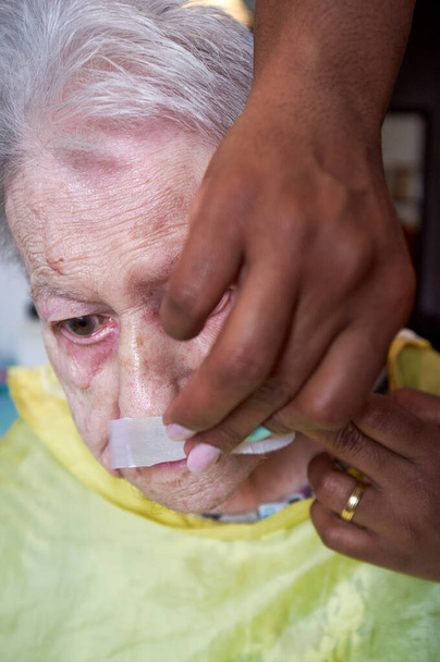 starsza kobieta otrzymująca depilację twarzy z afrykańskiej opieki amerykańskiej - Zdjęcie, obraz