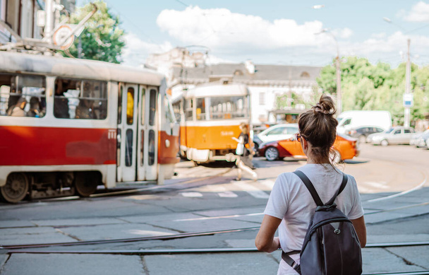 Podil, Kiev, Ucraina - 16 giugno 2021 - fotografia di strada di una giovane donna in attesa ad una fermata del tram con un tram vintage rosso a Podil, Kiev - Foto, immagini