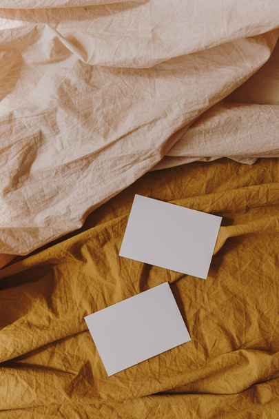 Blanco papieren uitnodigingskaarten met kopieerruimte op neutrale pastel elegante gember en perzik linnen doek. Flat lay, bovenaanzicht esthetische minimalistische bruiloft uitnodigingen - Foto, afbeelding