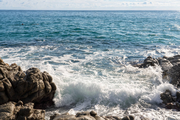 κύματα πέφτουν πάνω σε βράχια στη θάλασσα, αρκετά ήρεμη θάλασσα - Φωτογραφία, εικόνα