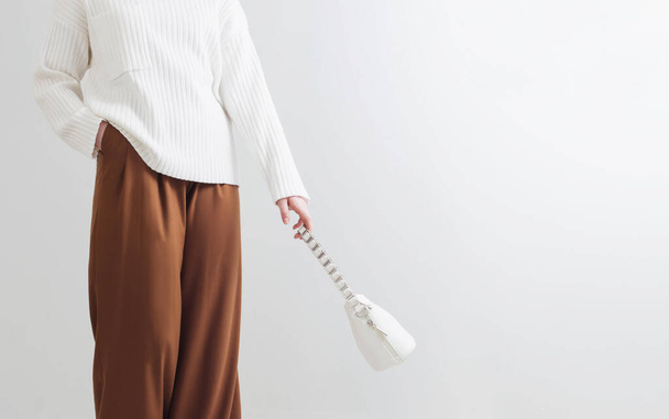 modern girl in white sweater and brown pants in white room - Zdjęcie, obraz